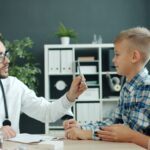 Doctor examines a young boy with his mother present.