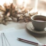white ceramic cup on white ceramic saucer beside red click pen